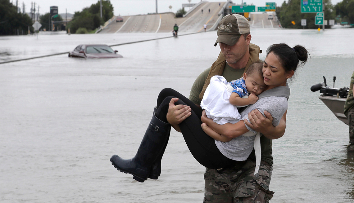 Daryl Hudeck carga a Catherine Pham y su hijo Aiden después de una inundación provocada por el huracán Harvey en Houston, en 2017.